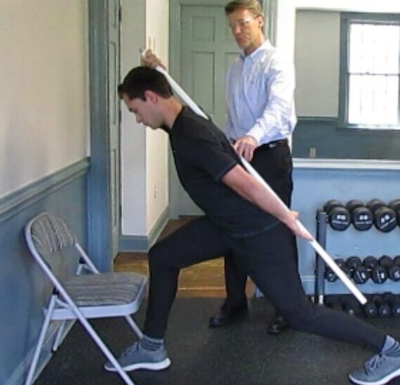 Man demonstrating posture correction exercise under chiropractic supervision in a wellness clinic